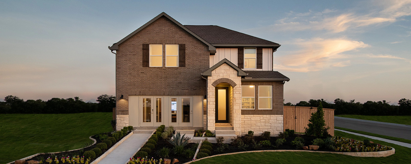 The Colony model home exterior at dusk, Bastrop